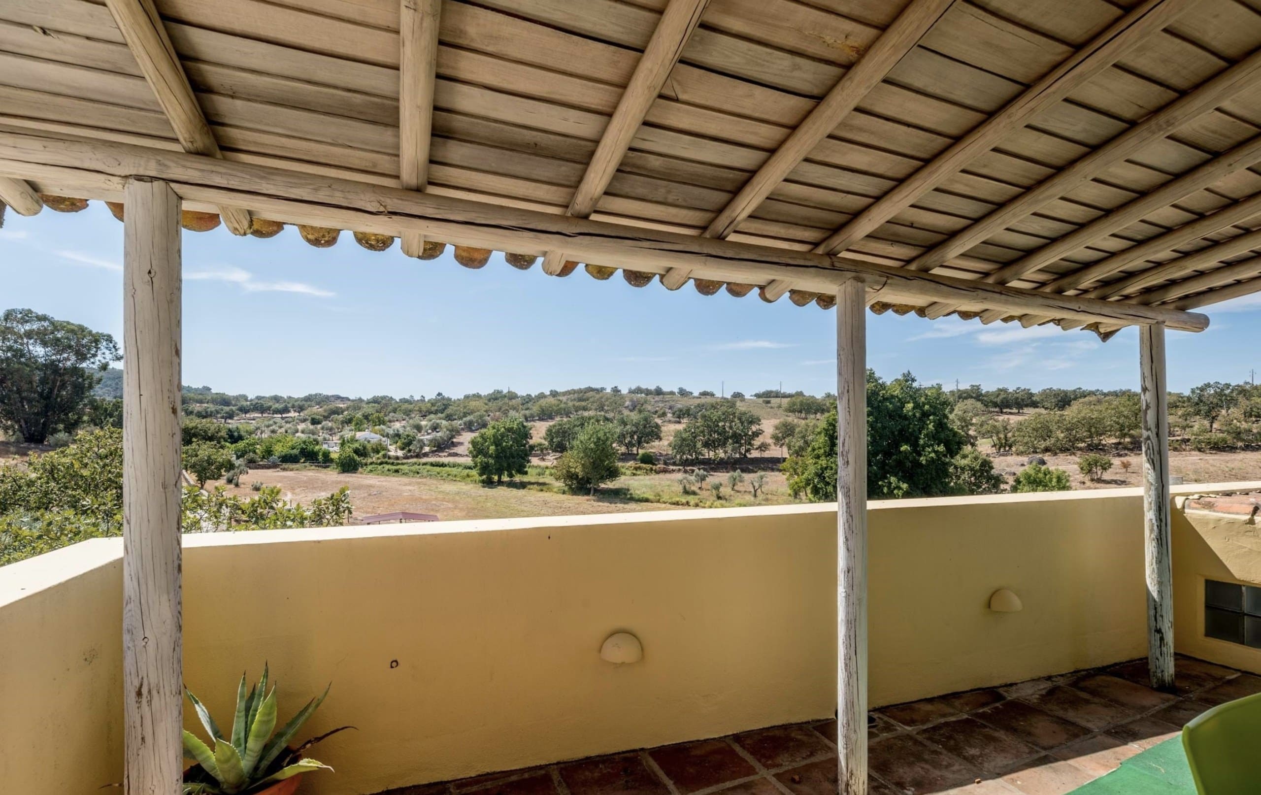 Blick von der überdachten Terrasse der Casa Grande über Olivenbäume und Korkeichen.