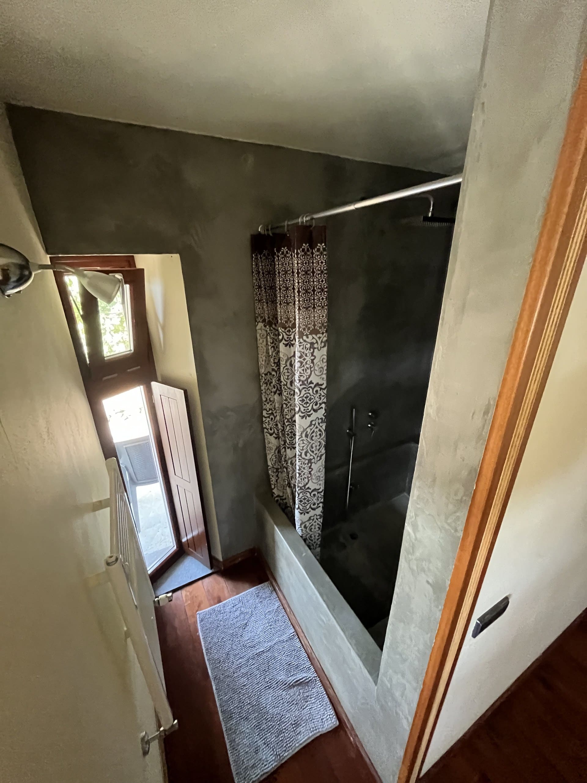 Bad der Casa Hridaya mit Regendusche über der Wanne und Tür ins Freie.
