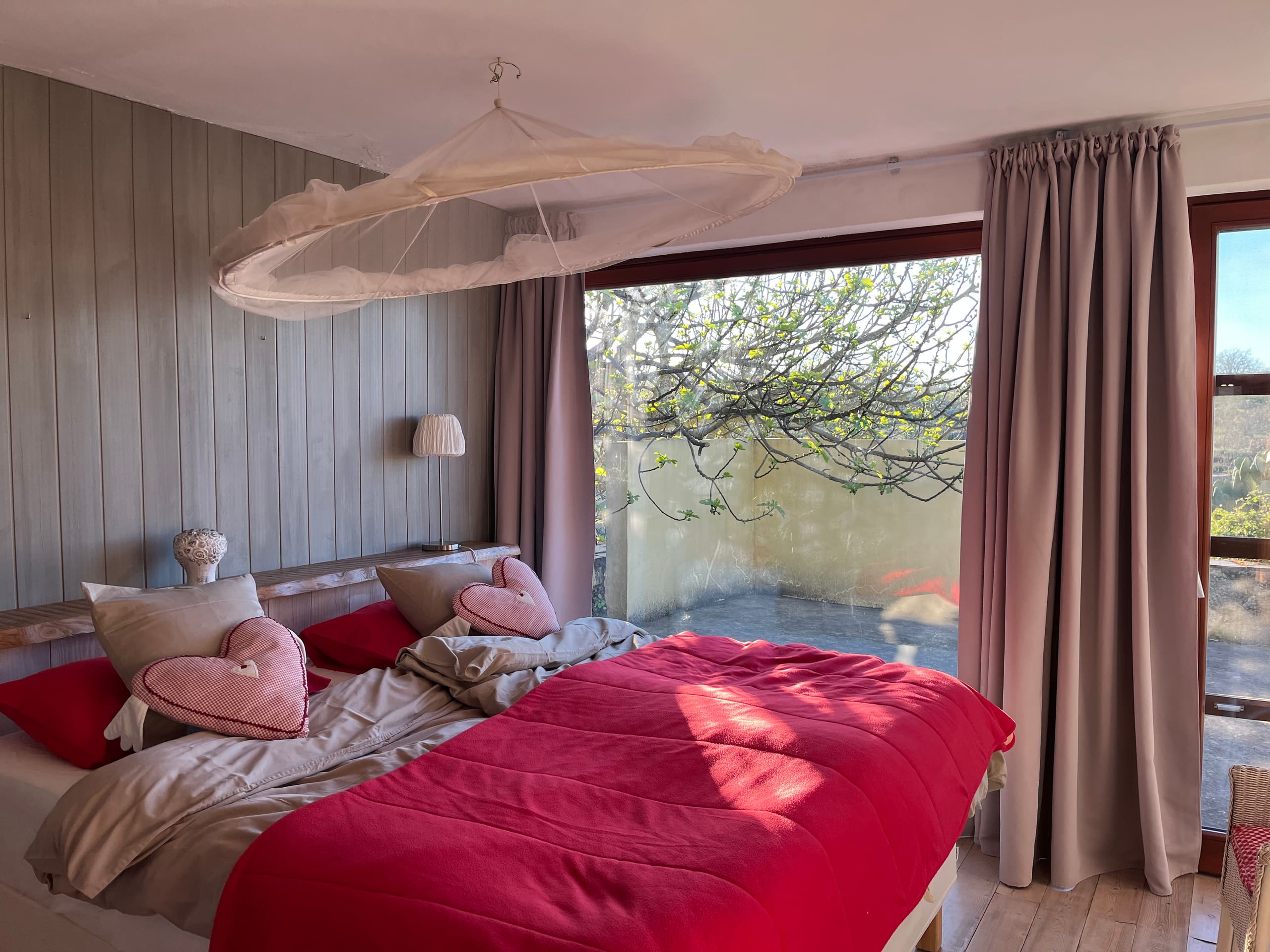 Schlafzimmer der Casa Amor Perfeito mit Doppelbett, Moskitonetz und Fenster zur Terrasse.