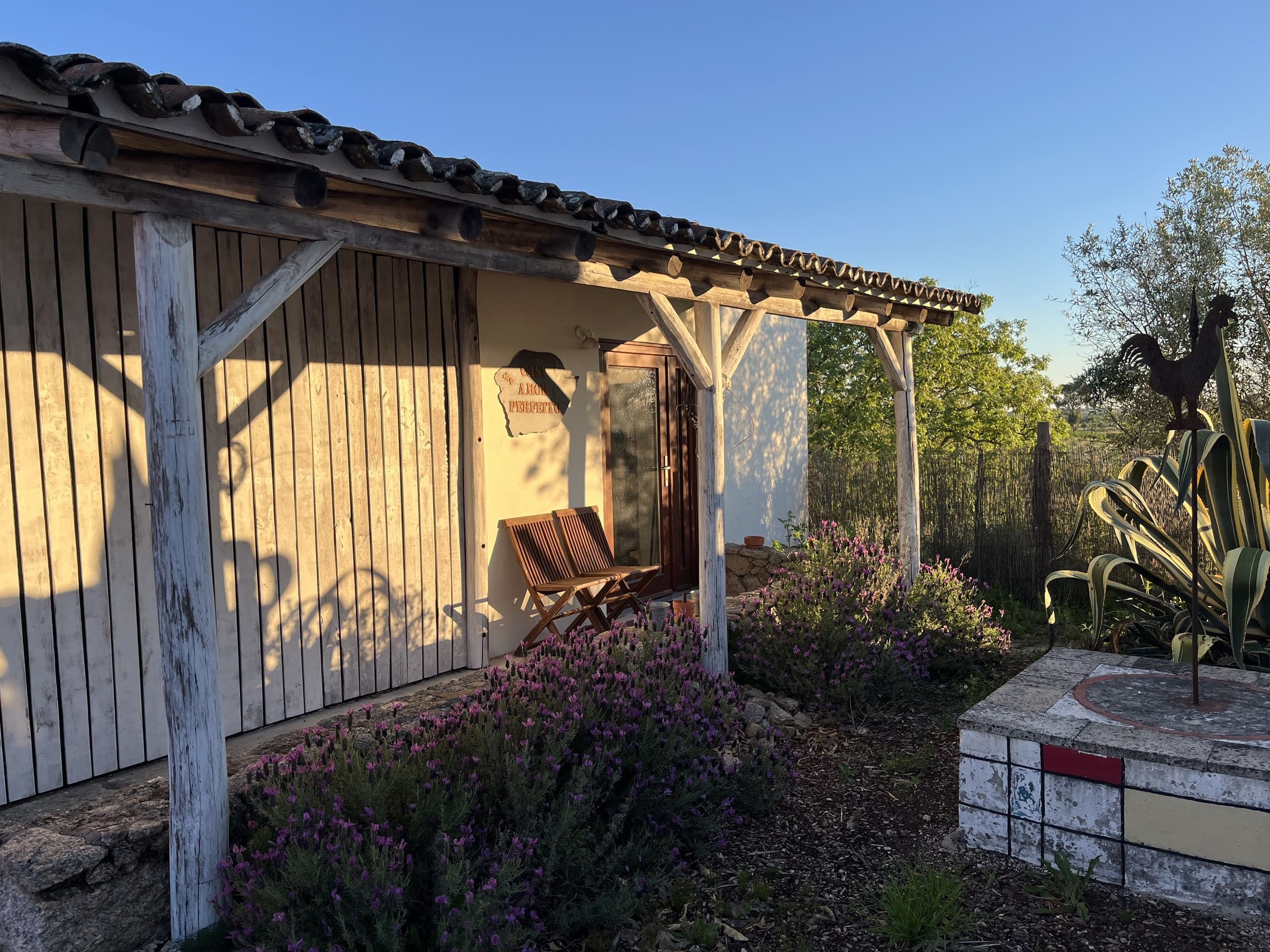 Das freistehende Häuschen Casa Amor Perfeito von außen, mit Namensschild, Vordach und blühendem Lavendel.