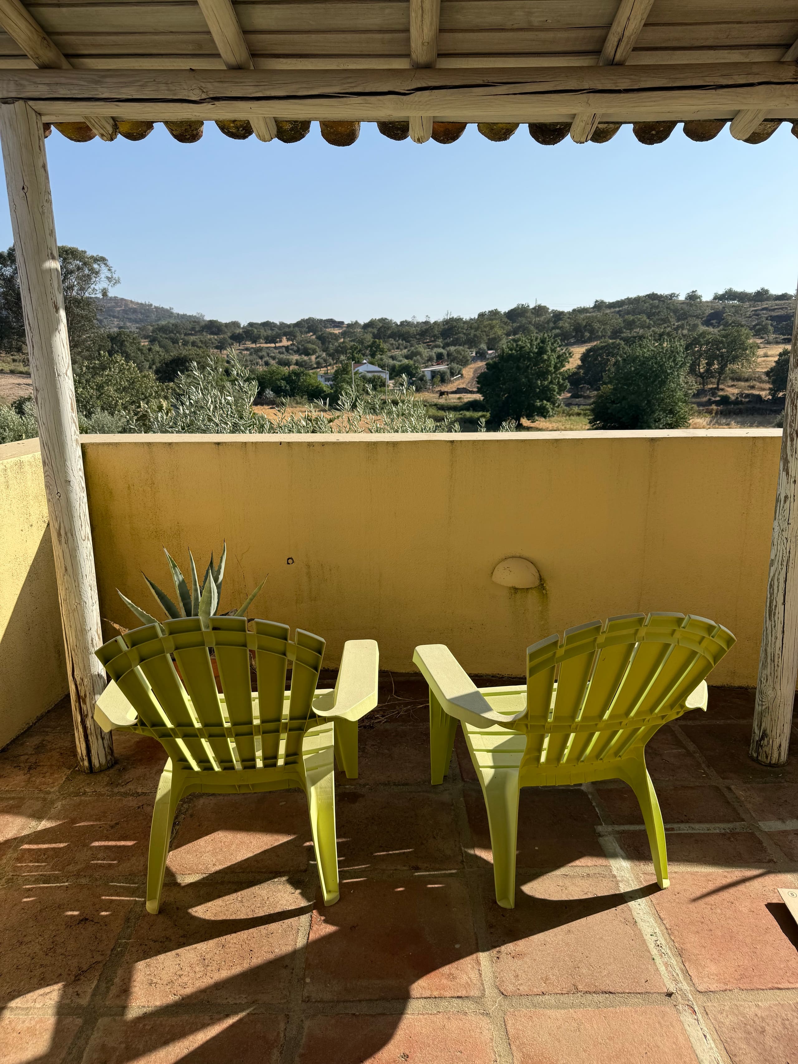 Zwei Liegestühle unter dem Holzdach der Terrasse der Casa Grande mit Blick in die Landschaft.