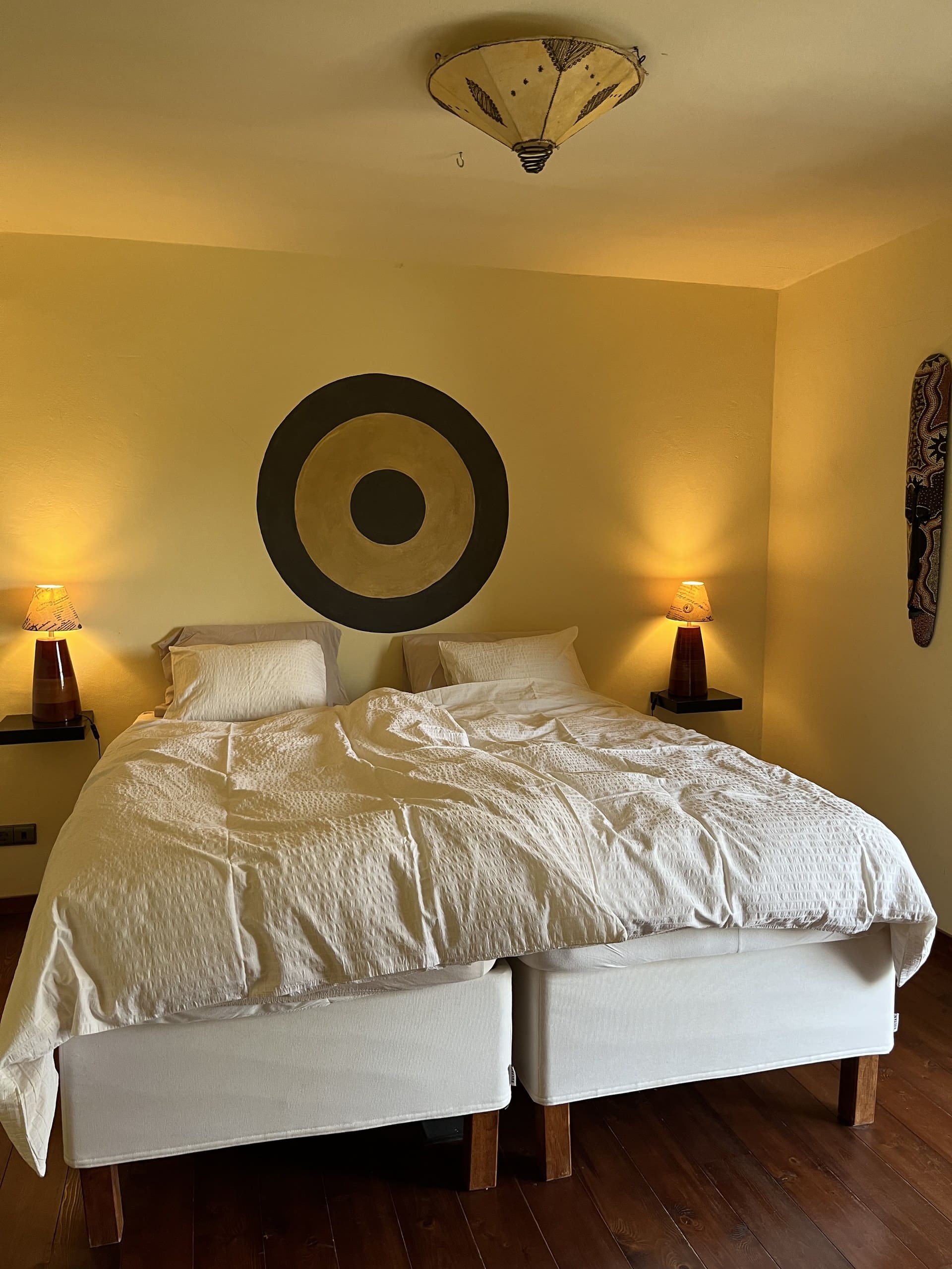 Bett im Schlafzimmer der Casa Hridaya im Licht der beiden Nachttischlampen.