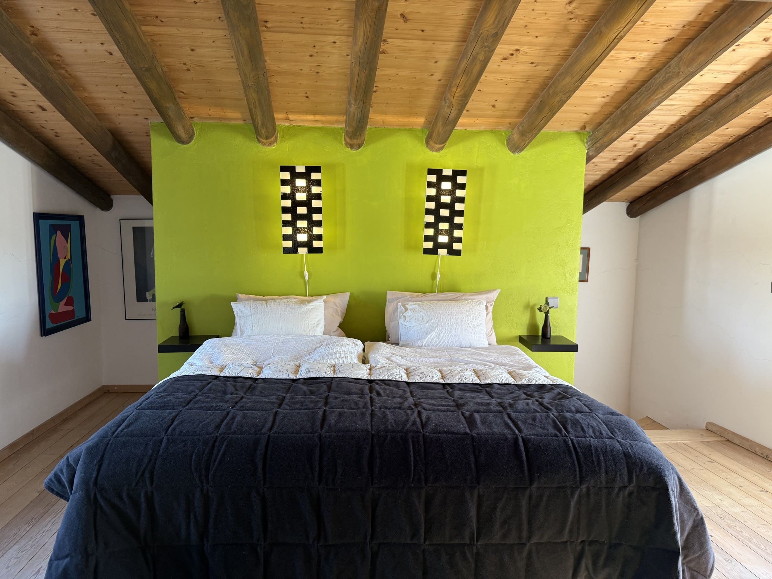 Kopfende des Doppelbetts vor der limettengrünen Wand mit zwei Wandleuchten in der Casa Grande.