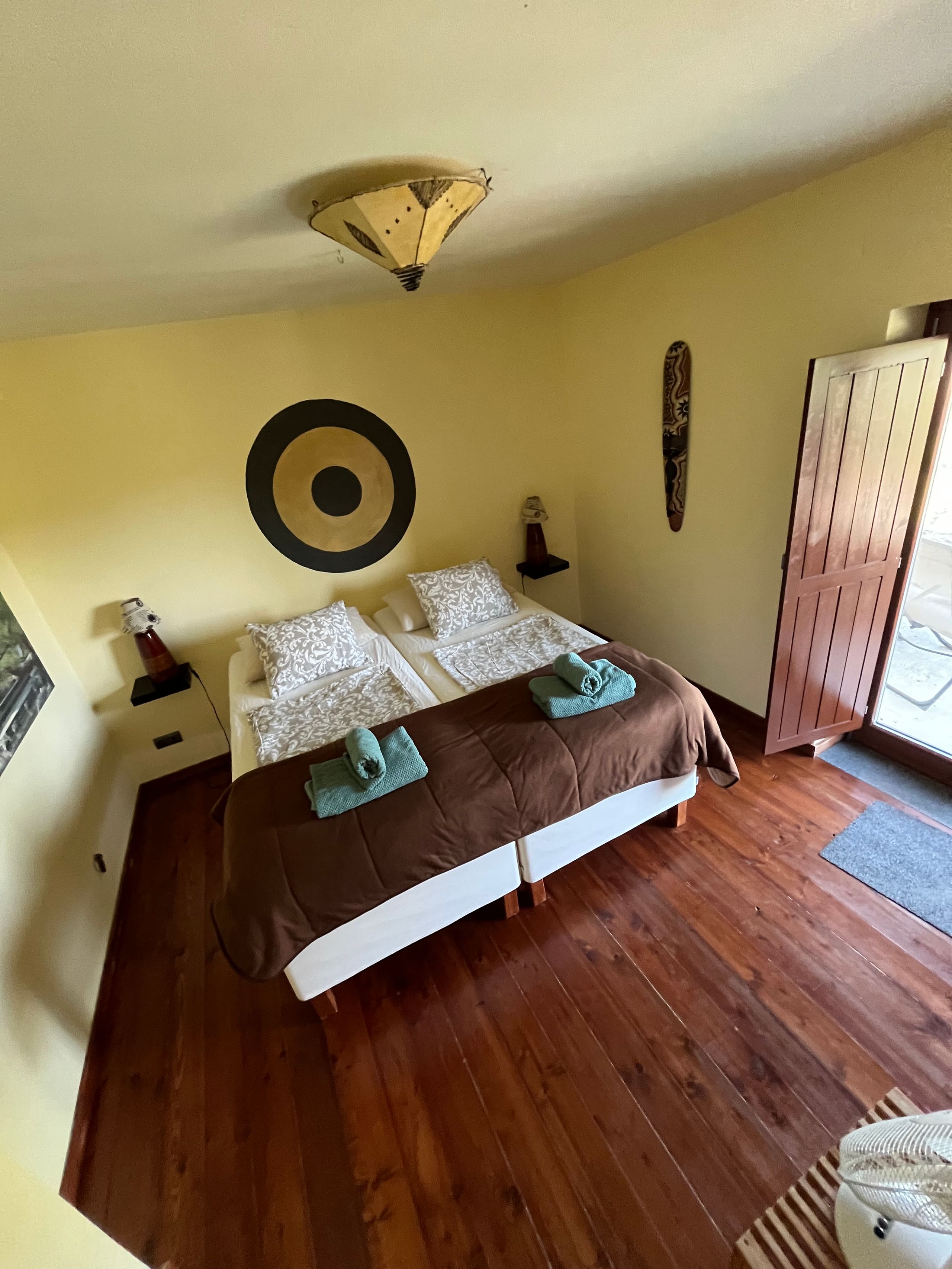 Schlafzimmer mit gelber Wand in der Casa Hridaya, die Tür zur Terrasse steht offen.