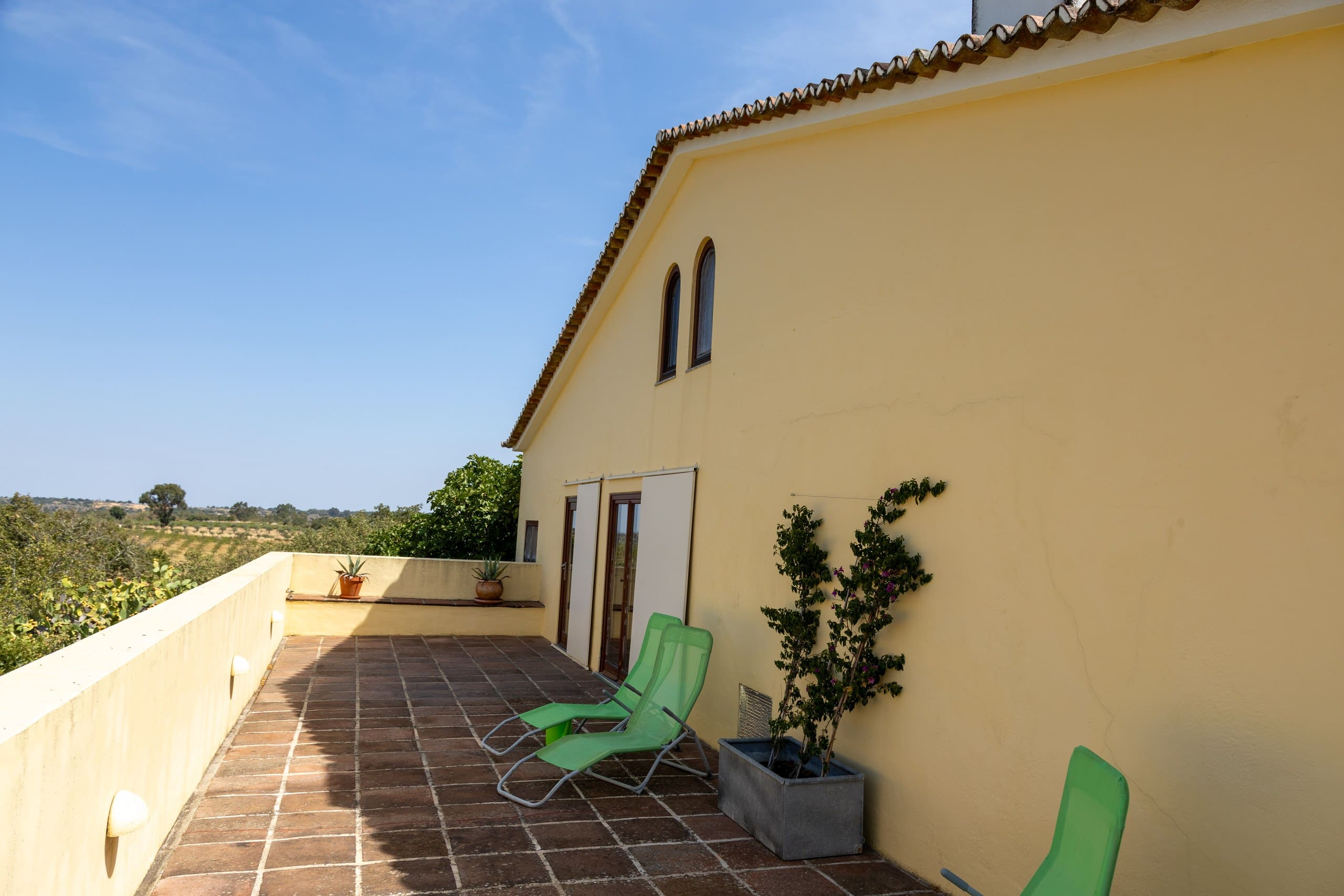 Dachterrasse der Casa Grande mit zwei grünen Sonnenliegen an der gelben Hauswand.