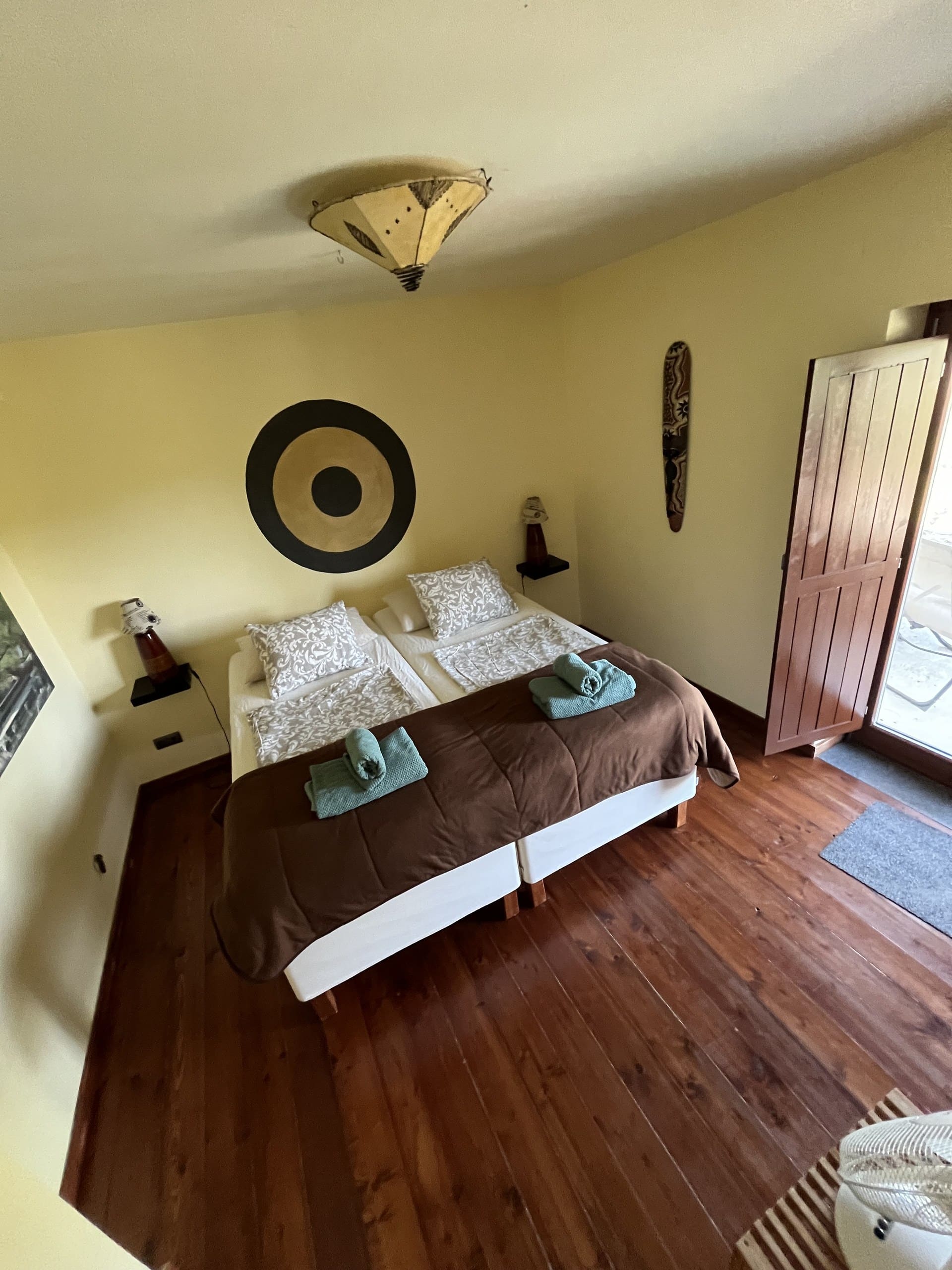 Schlafzimmer mit gelber Wand in der Casa Hridaya, die Tür zur Terrasse steht offen.