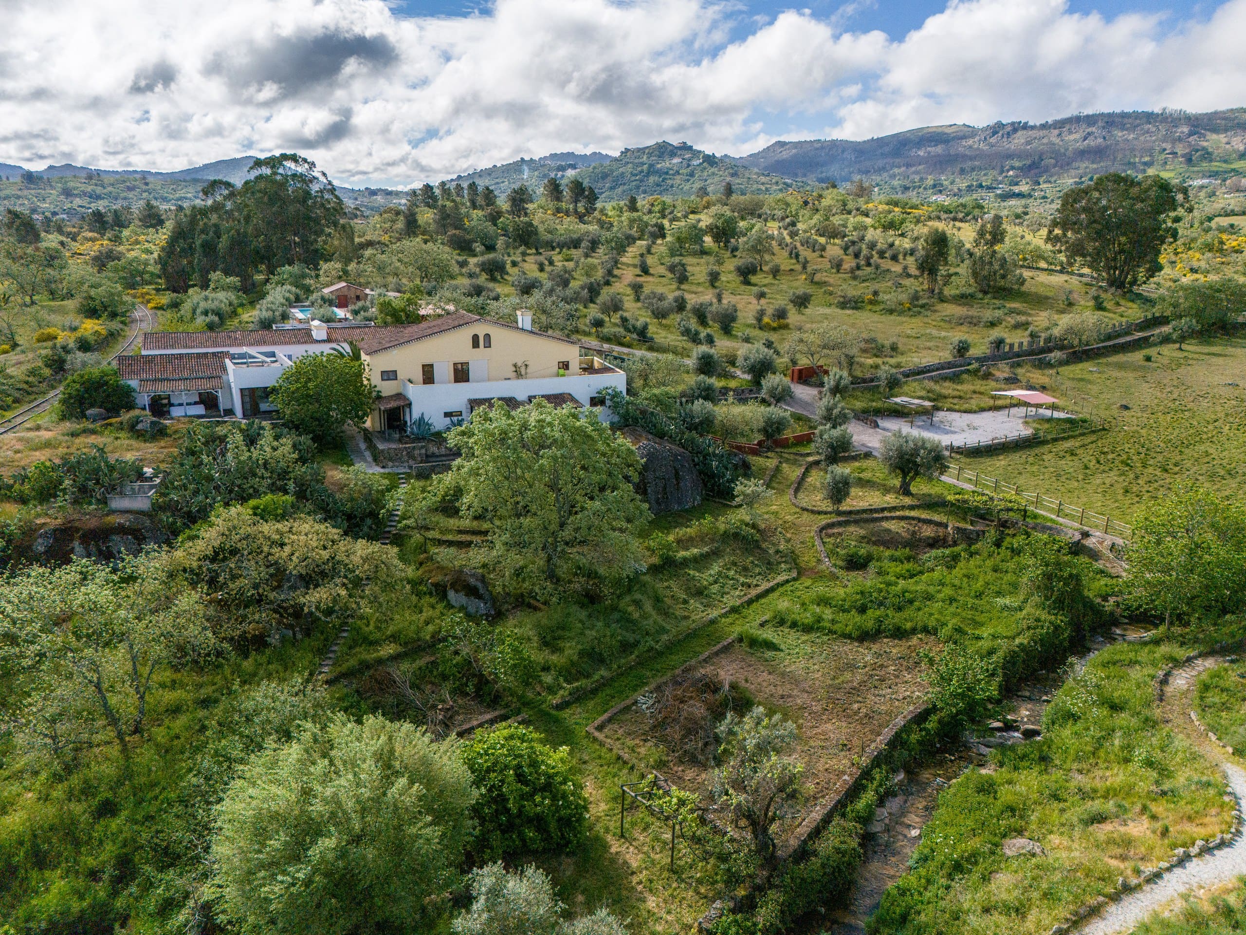 Luftbild der Quinta Serra de São Mamede: das Haupthaus mit Terrakottadach, davor die Gartenterrassen, dahinter Olivenhain und die Berge der Serra.