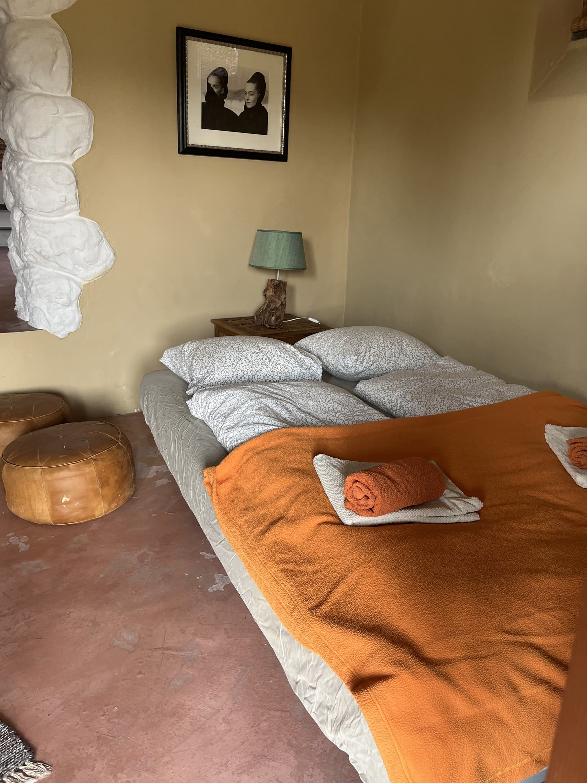 Frische Handtücher auf dem bezogenen Bett der Casa Terra, im Hintergrund der weiß gestrichene Granitfelsen.