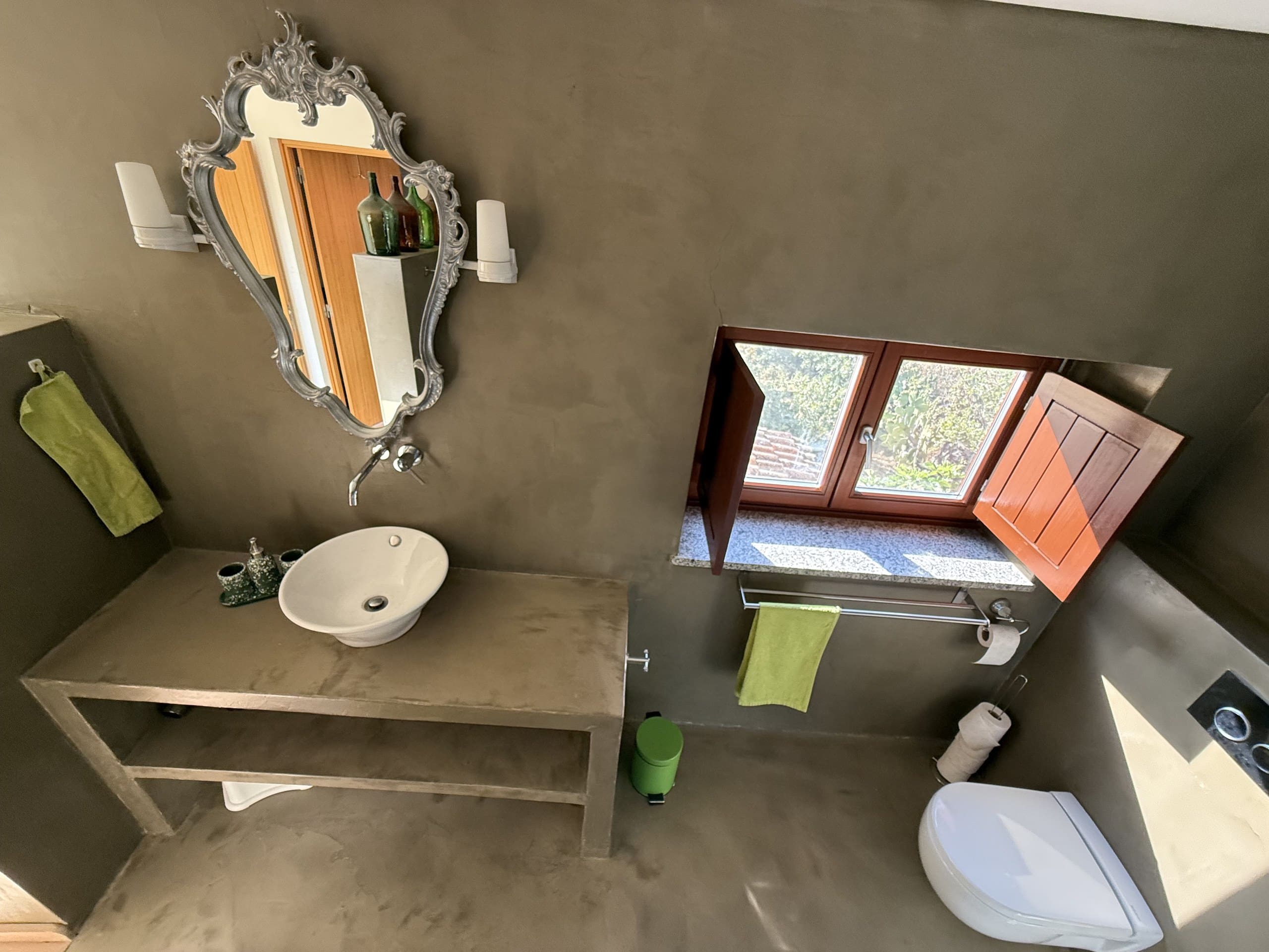Bad der Casa Grande mit Aufsatzwaschbecken, Zierspiegel und geöffnetem Fenster.