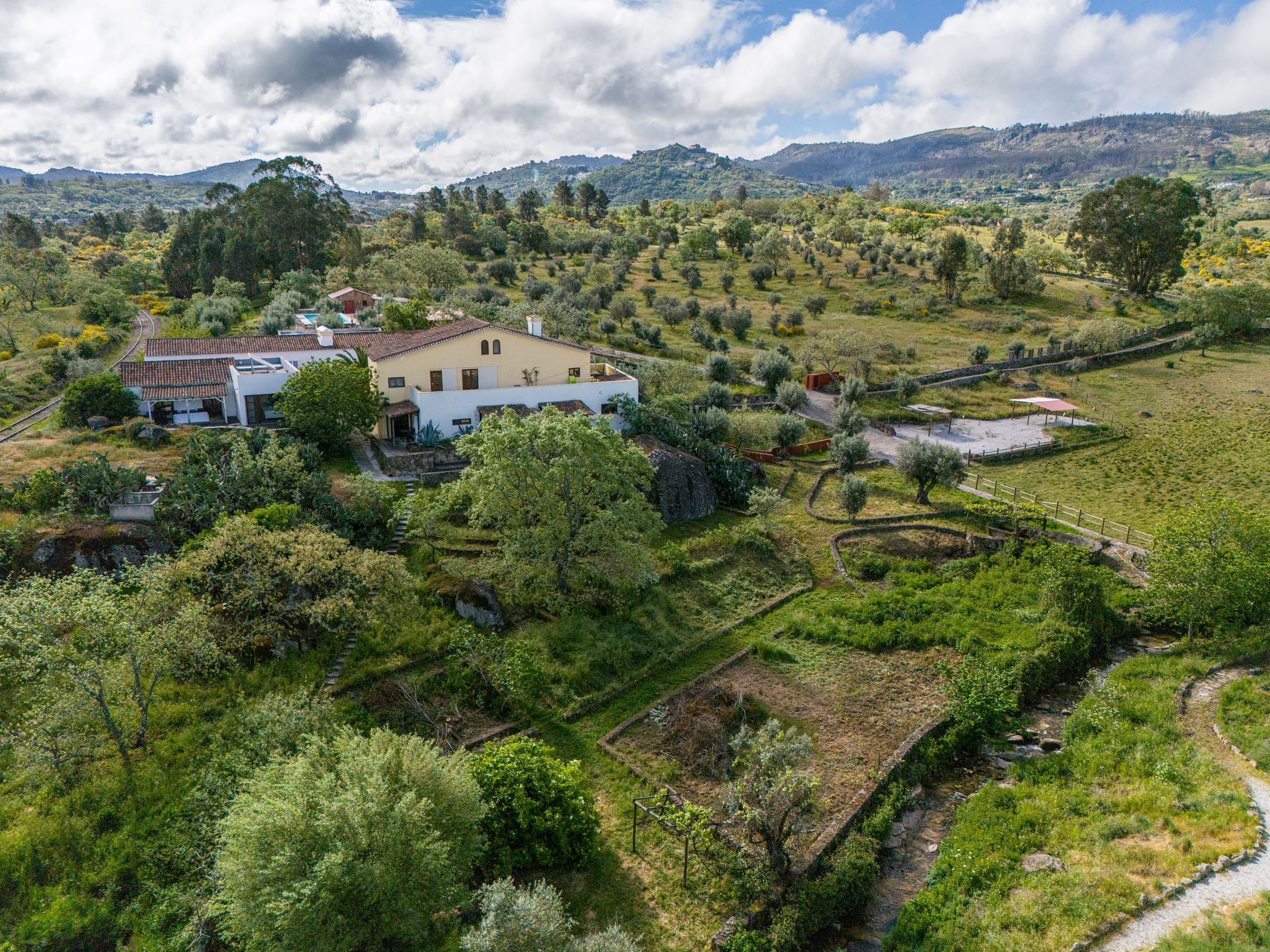 Luftbild der Quinta Serra de São Mamede: das Haupthaus mit Terrakottadach, davor die Gartenterrassen, dahinter Olivenhain und die Berge der Serra.