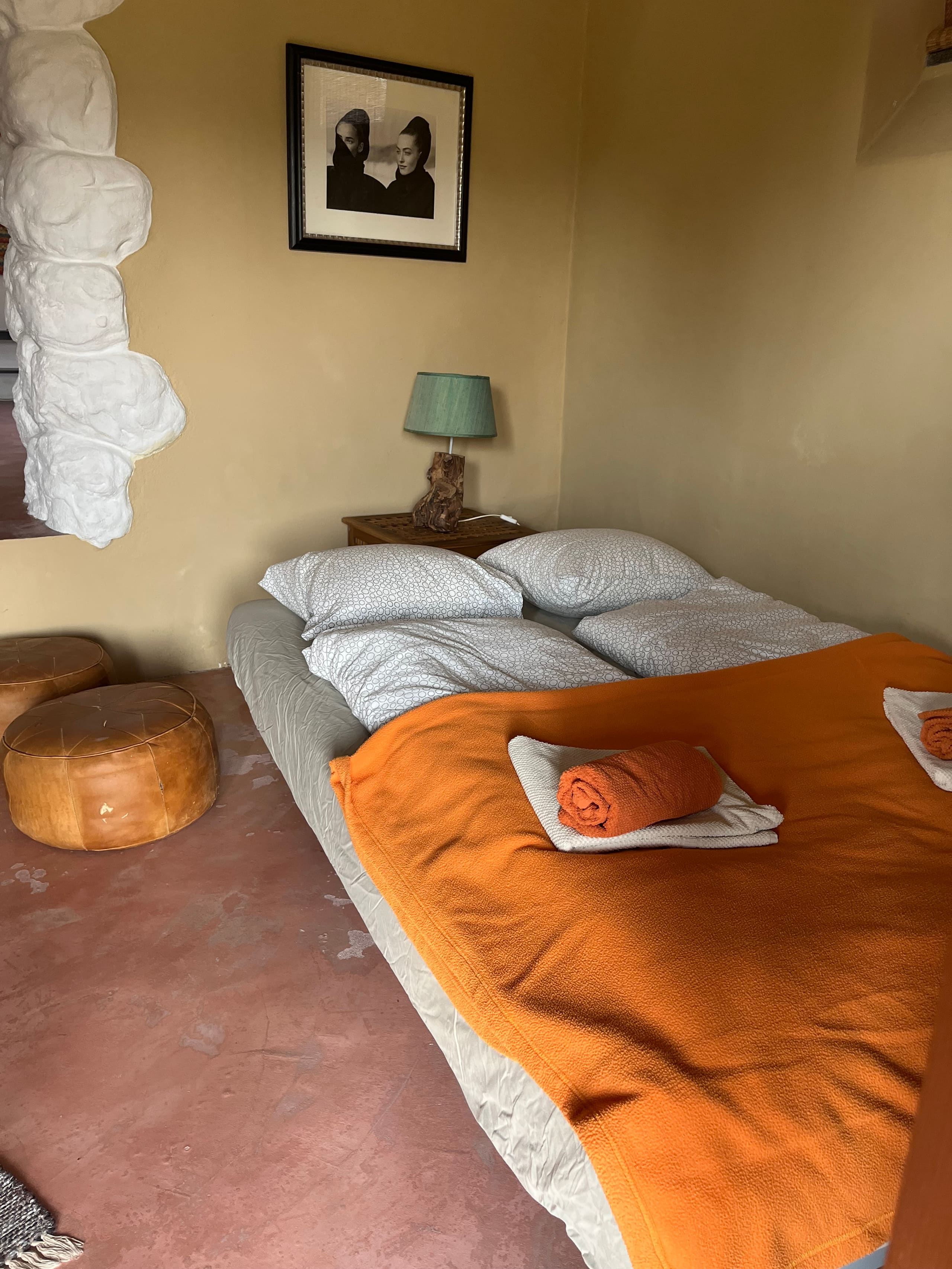 Frische Handtücher auf dem bezogenen Bett der Casa Terra, im Hintergrund der weiß gestrichene Granitfelsen.