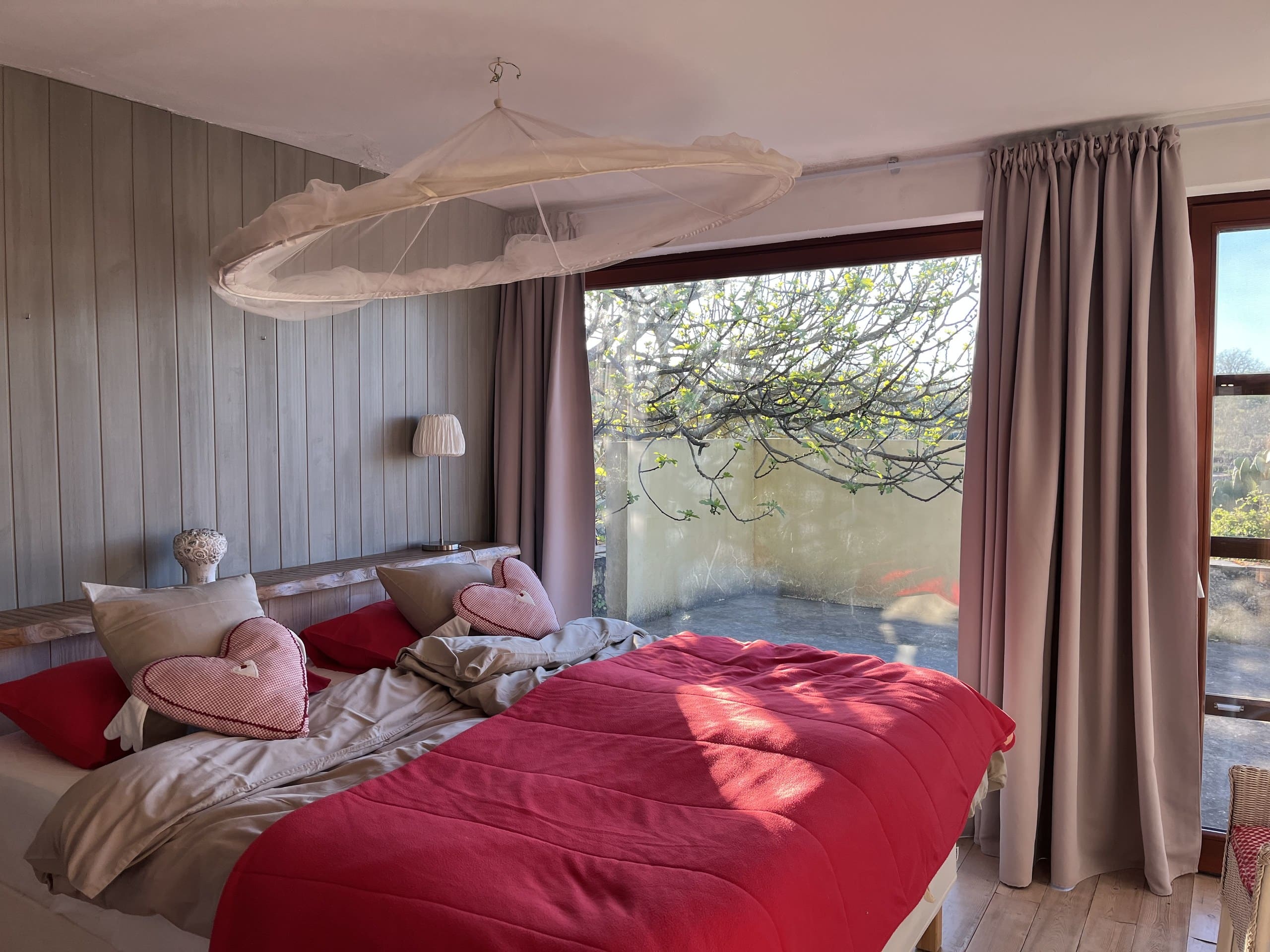 Schlafzimmer der Casa Amor Perfeito mit Doppelbett, Moskitonetz und Fenster zur Terrasse.