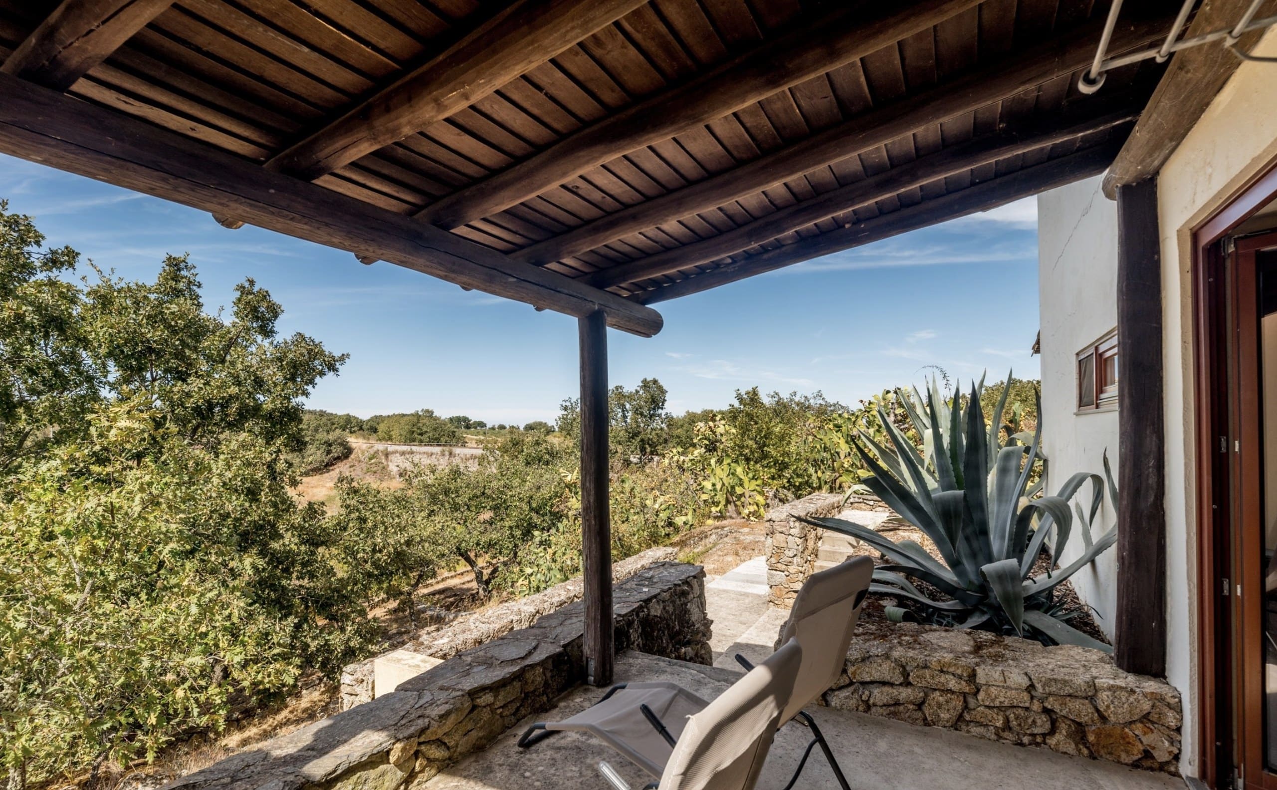 Blick von der überdachten Terrasse der Casa Hridaya über Bäume und Felder.