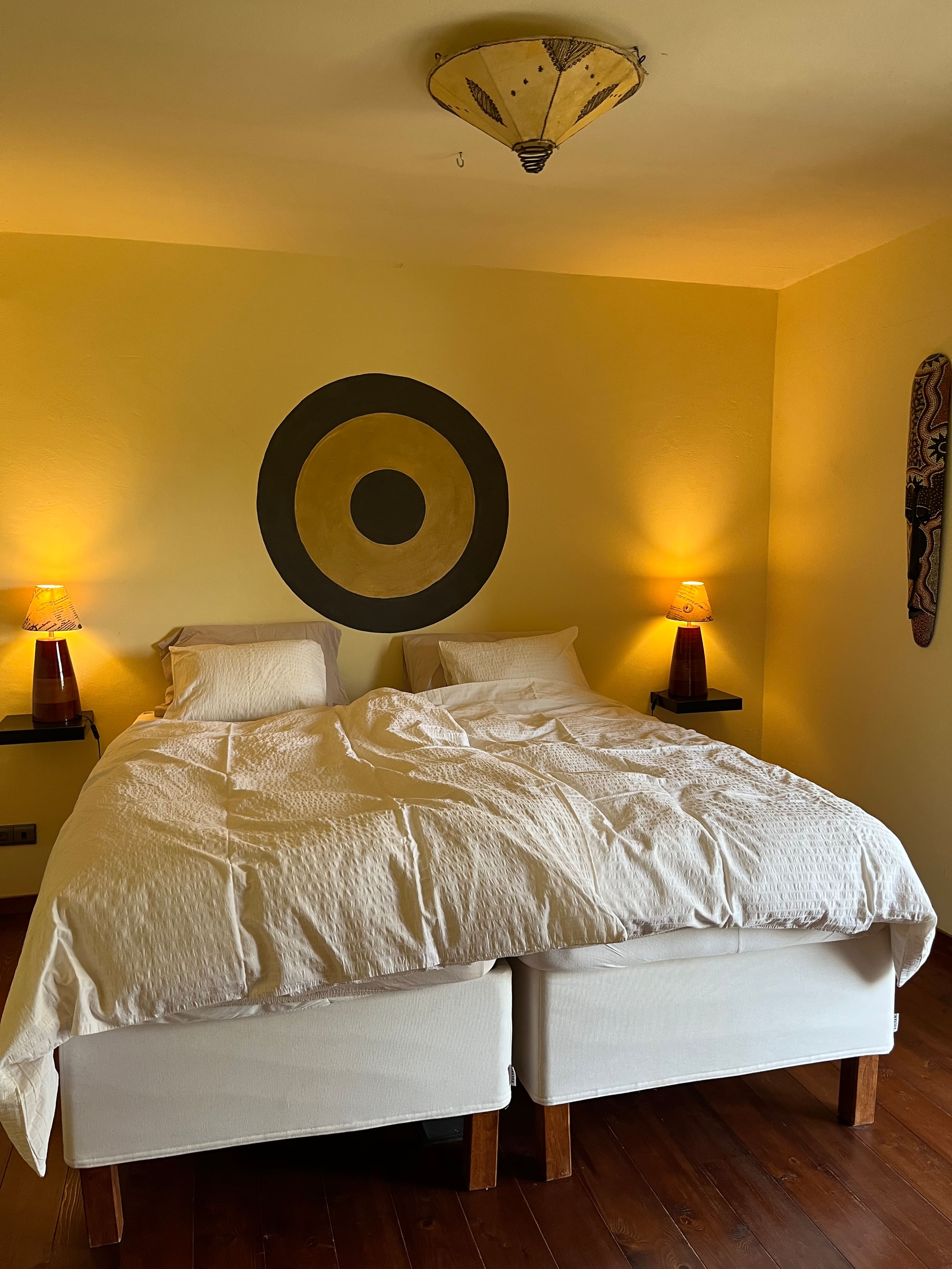 Bett im Schlafzimmer der Casa Hridaya im Licht der beiden Nachttischlampen.