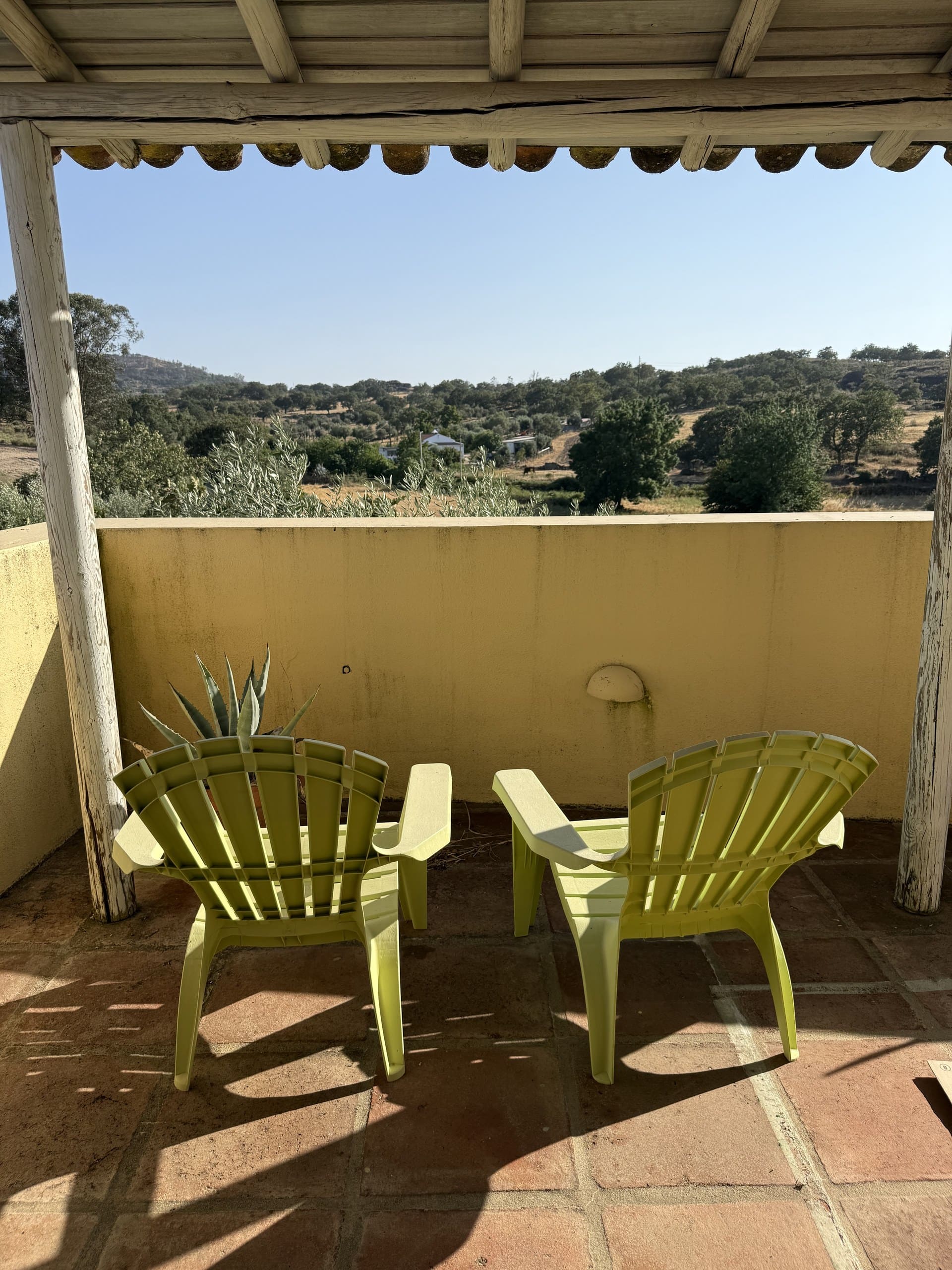 Zwei Liegestühle unter dem Holzdach der Terrasse der Casa Grande mit Blick in die Landschaft.