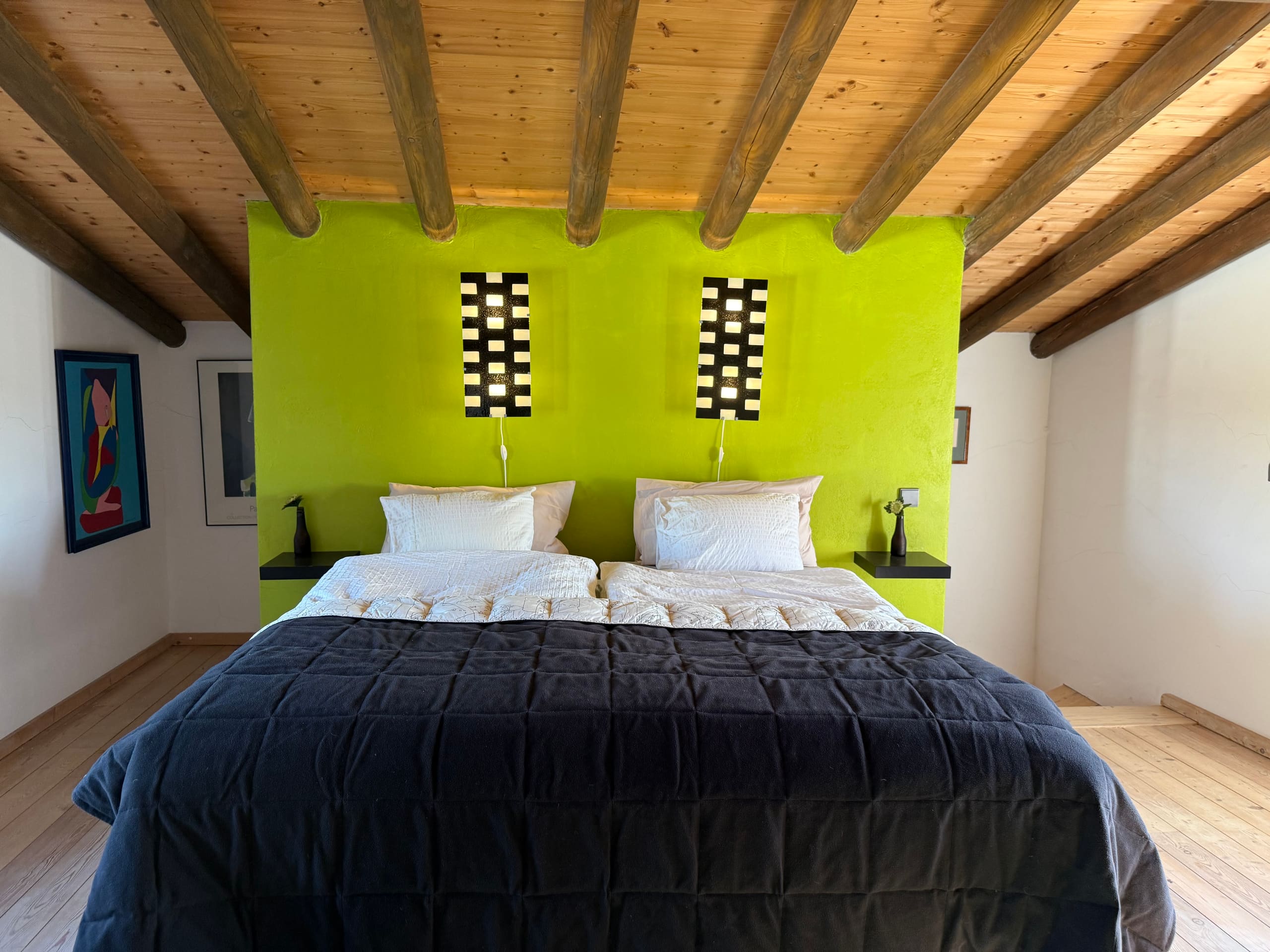 Kopfende des Doppelbetts vor der limettengrünen Wand mit zwei Wandleuchten in der Casa Grande.